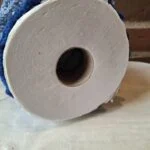 Undersiden af et blåt hæklet skørt med en toiletrulle i åbningen.