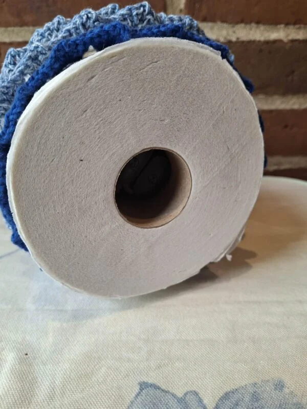 Undersiden af et blåt hæklet skørt med en toiletrulle i åbningen.