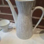 Rosenthal Bavaria kaffekande i hvid porcelæn med et gråt, flettet grafisk mønster, set fra siden med tud og hank.