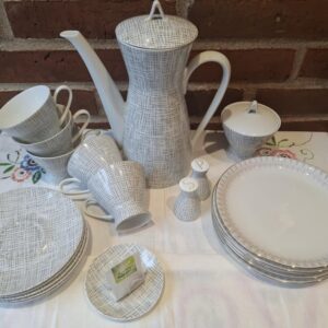 Et stort Rosenthal kaffeservice i hvid porcelæn med et gråt, flettet grafisk mønster. Inkluderer kaffekande, kopper, underkopper, tallerkener, sukkerskål og salt/peberbøsser.