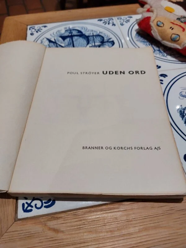 Nærbillede af forsiden på 'UDEN ORD' af Poul Strøyer, der fremhæver den ikoniske tegning og gule taleboble.