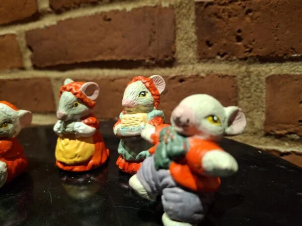 Middelstort foto af to musselmalede keramikmusefigurer. Den ene bærer blåt og orange tøj, den anden holder en kurv.