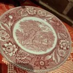 Rød transferware tallerken fra Wood & Sons England, 22 cm, med et detaljeret landskabsmotiv og blomsterkant.