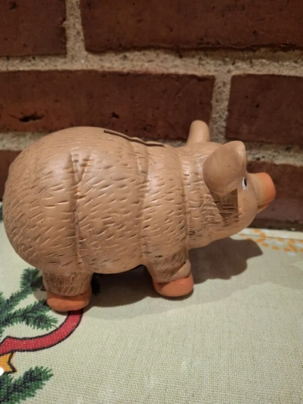 En terracotta sparegris set fra siden, der viser dens karakteristiske form og strukturerede overflade. På juledug.