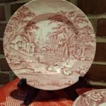Rød transferware tallerken fra Midwinter Stylecraft County Manor, 22 cm, med et landligt motiv af hus og træer.