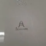 Bagsiden af en hvid Aluminia fajancetallerken, der tydeligt viser stemplet 'Aluminia Denmark' med et stillet A-logo.