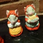 Nærbillede af to musselmalede keramikmusefigurer. Den ene mus bærer rød hue, den anden holder en kurv.