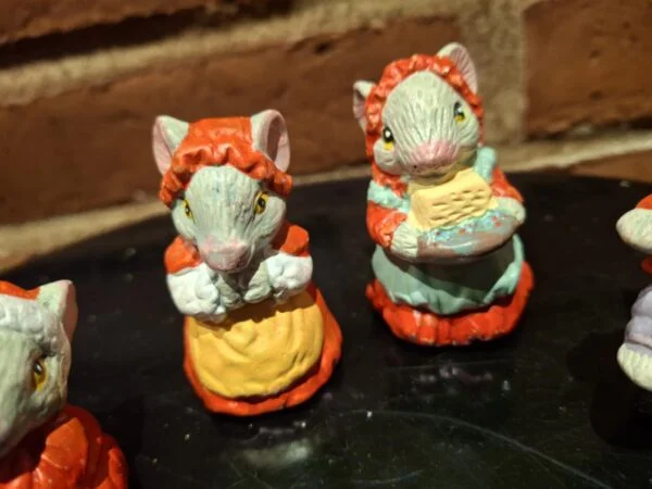 Nærbillede af to musselmalede keramikmusefigurer. Den ene mus bærer rød hue, den anden holder en kurv.