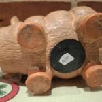 Undersiden af en terracotta sparegris, der viser en gummiprop og et hvidt prisskilt med '80' kr.