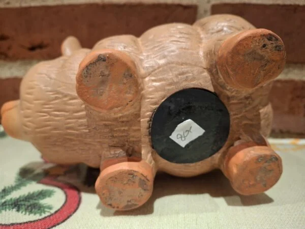 Undersiden af en terracotta sparegris, der viser en gummiprop og et hvidt prisskilt med '80' kr.