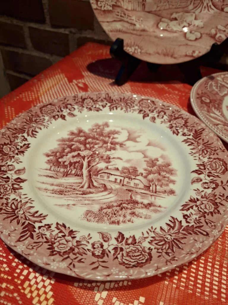 En klassisk rød transferware middagstallerken, 22 cm, fra W.H. Grindley i 'Country Style' med et landligt motiv.