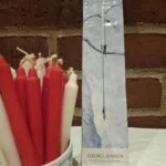 Lys emballage med Georg Jensen-navn, Christmas Nordica og en tegning af lyseholderen; røde og hvide lys står ved siden af.