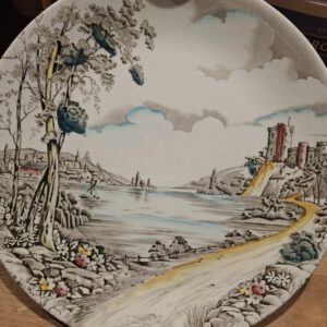 En engelsk middagstallerken 'Alton British Anchor' med et idyllisk landskabs- og borgmotiv i grå og gule nuancer på en træoverflade.