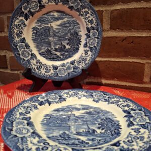 To engelske, blå-hvide vintage tallerkener med et romantisk landskabsmotiv af et skotsk loch, den ene på stativ, den anden liggende.