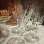 Nærbillede af en champagnefløjtes snoede mønster, dekorative stilk og runde fod; et andet glas står bagved.