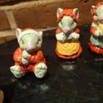 Nærbillede af to musselmalede keramikmusefigurer. Den ene mus bærer rød frakke og den anden sover i en gul kop.