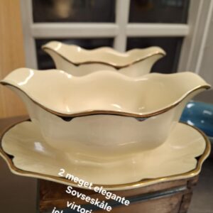 To elegante sovseskåle i cremefarvet porcelæn fra Johnson Bros. 'Victorian' stil, med guld- og mørkeblå kanter, placeret på en træbase. Teksten '2 meget elegante Sovseskåle virtorian johnson bros England' er på billedet.