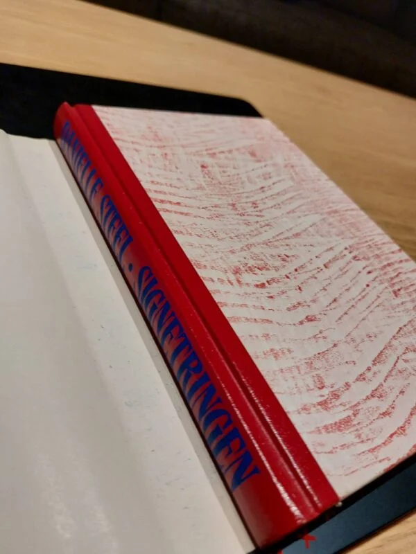 Lukket eksemplar af Signetringen med rødt, mønstret bind.