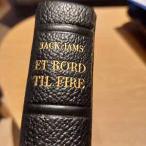 Sort læderryg med guldtryk på bogen 'Et Bord til Fire'