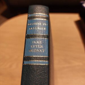 Ryg af bogen 'Ikke Efter Midnat' med blå og guldfarvede detaljer