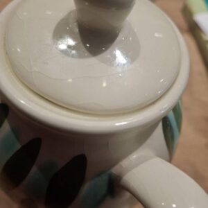 Nærbillede af tekandens låg med lys porcelæn og grønne blade