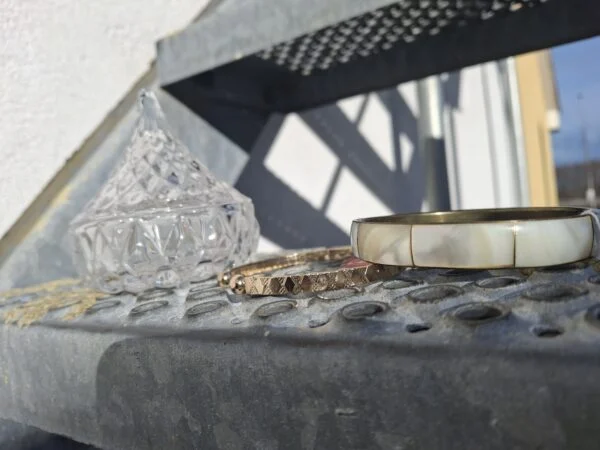 To gyldne armbånd på trappe ved siden af glasbeholder