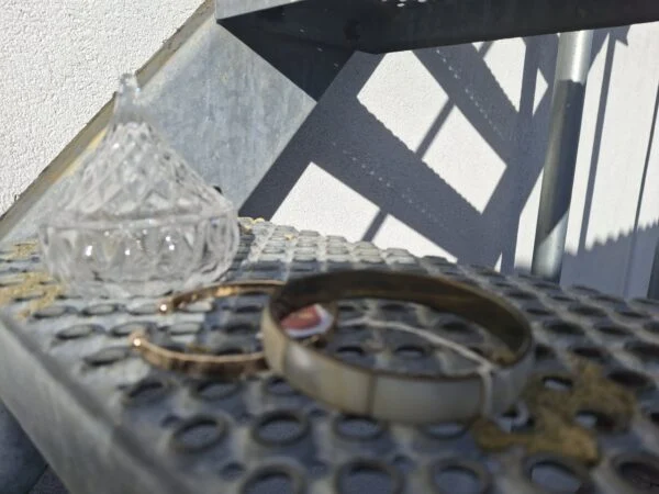 Gyldent retro armbånd på metaltreppe nær glasbeholder