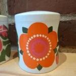 Krukke med orange blomster og hvidt låg