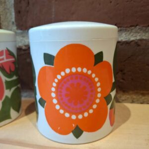 Farverig retro krukke med orange blomst og låg