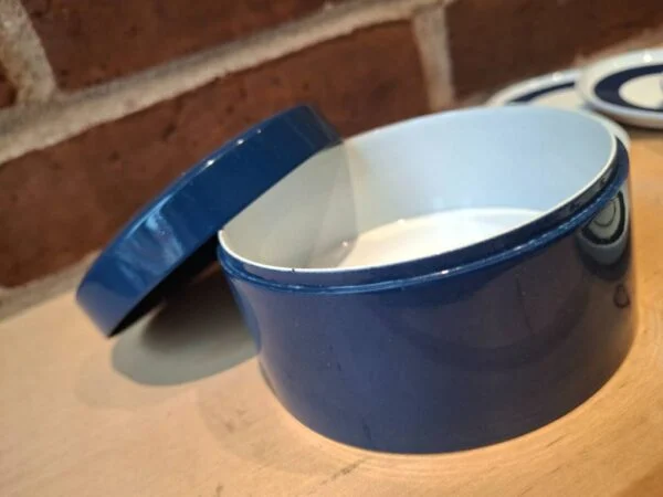 Åben blå coasterholder med låget ved siden af