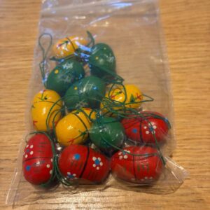 Farverige håndmalede træpåskeæg i rød, gul og grøn med mønstre og blomsterdetaljer