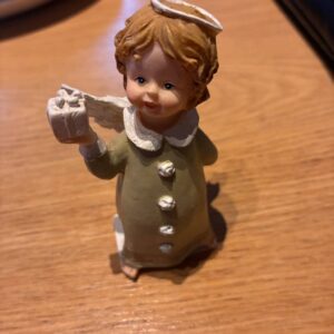 Englefigur med grøn kjole, gave og glorie på træbord