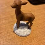 Brun dådyrfigur på snebelagt sokkel
