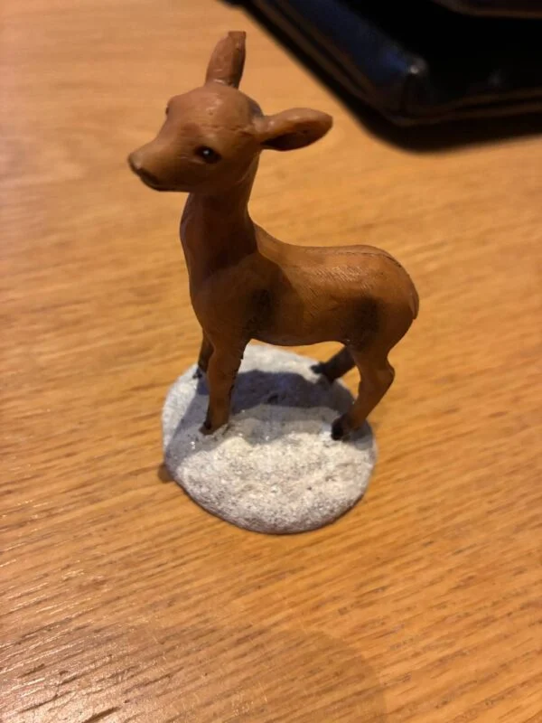 Brun dådyrfigur på snebelagt sokkel