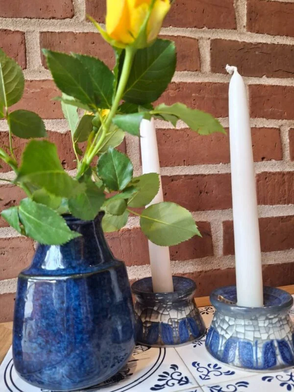 To blå Michael Andersen-lysestager ved en separat L. Hjorth-vase med blomster, opstillet på en tallerken.