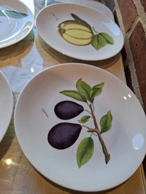 To porcelænstallerkener med frugtillustrationer: blommer og kvæde