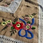 Håndbroderet hør dug med blomsterbroderi og blondekant tæt på