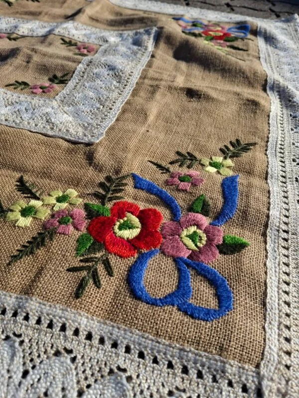 Håndbroderet hør dug med blomsterbroderi og blondekant tæt på