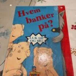 Forsiden af børnebogen 'Hvem banker på?' med illustration af tre grise og en ulv