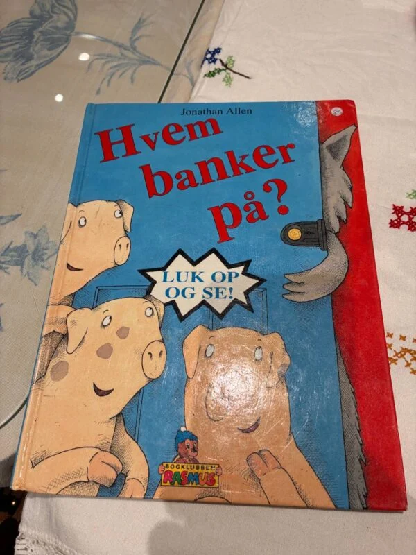 Forsiden af børnebogen 'Hvem banker på?' med illustration af tre grise og en ulv