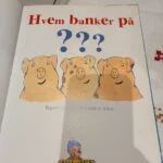 Indersiden af bogen 'Hvem banker på?' med titlen og illustrationer af grise