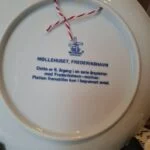 Bagside af Møllehuset-platten med Millhouse Danmark-mærke, tekst om 6. årgang og rød-hvid ophængssnor.