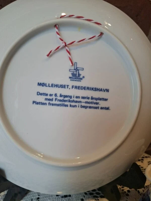 Bagside af Møllehuset-platten med Millhouse Danmark-mærke, tekst om 6. årgang og rød-hvid ophængssnor.