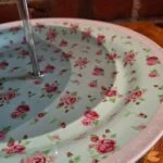 Detalje af kagefadets nederste etage med rosa roser, lys kant og sølvfarvet midterstang.
