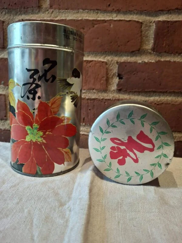 Metaldåse med rødt blomstermotiv og kinesiske tegn