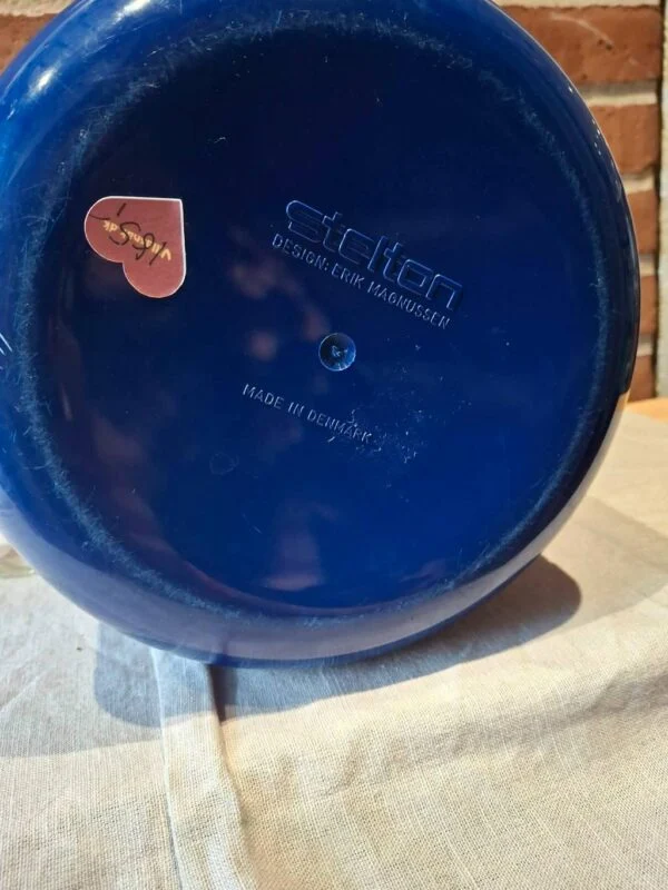 Stelton-logo og designtekst på blå is-spand bund