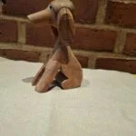 Træfiguren af hund set fra siden mod mur