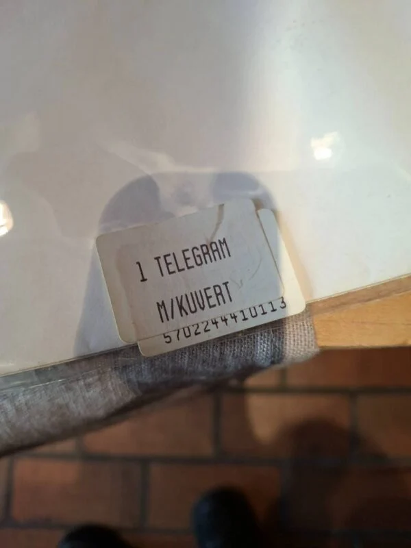 Bagside af emballage med stregkode og mærkaten “1 telegram m/kuvert”.
