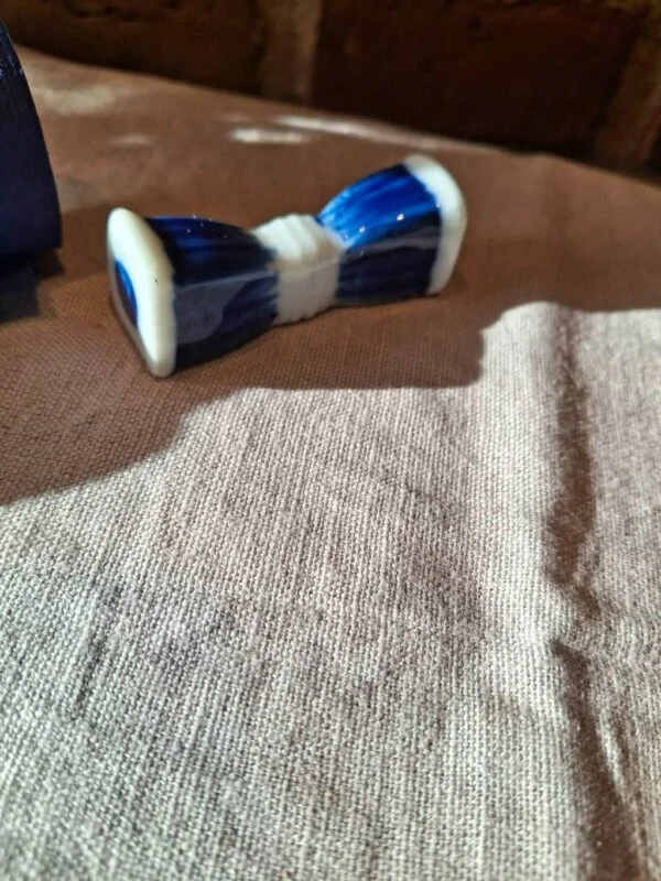 Blå-hvid porcelænsholder med brede ender og en indsnævret midte på en lys dug.