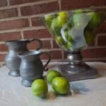 Sæt med 2 tin kander i rustik stil på hvid dug med limefrugter og glasbowle